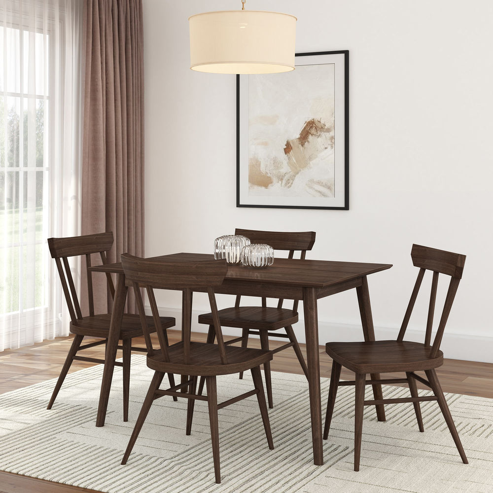 Mid-century modern dining room with dark wood table and chairs set on a light woven rug in a bright interior space.