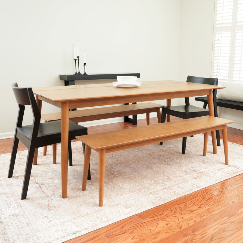 Modern dining room with wooden table, black chairs, and bench on a stylish rug.
