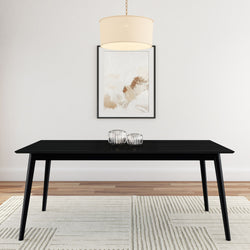 Modern black dining table with glass candle holders, white textured rug, and abstract wall art in contemporary dining room setup.