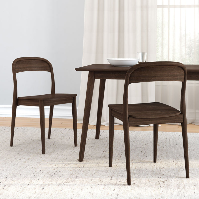 Mid-century modern dark walnut dining table with two matching wooden chairs on a neutral textured rug in a minimalist dining room with sheer curtains and natural light