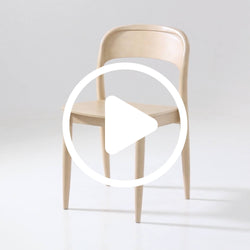 Minimalist light wood bentwood dining chair with curved back and tapered legs on white studio background.