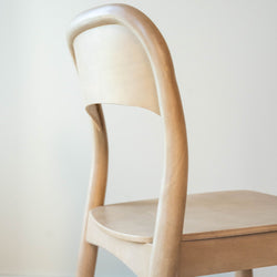 Minimalist wooden chair with curved backrest in modern interior design.