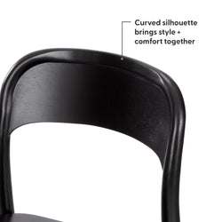 Close-up of a black curved wooden dining chair back with ergonomic silhouette and matte finish, modern bistro-style chair on white background