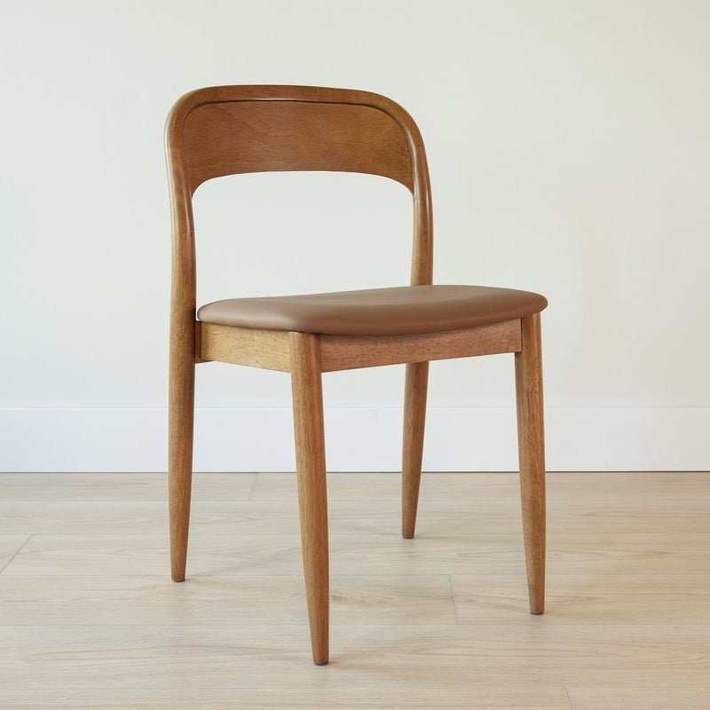 Mid-century modern oak dining chair with brown leather upholstered seat and curved backrest on light wood floor, minimalist Scandinavian design