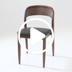 Walnut mid-century modern dining chair with curved backrest, black leather upholstered seat and tapered legs on white background, video play icon overlay
