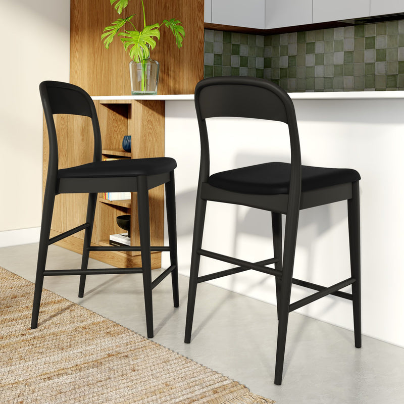 Modern black bar stools in kitchen with wood paneling and green accent tiles.