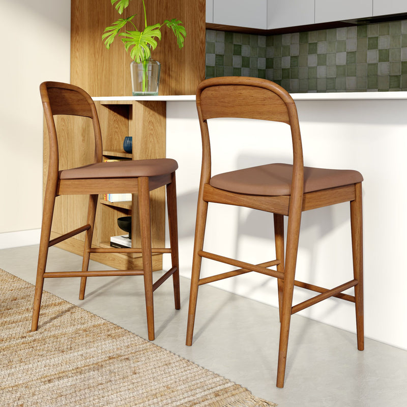 Mid-century modern wooden bar stools with brown leather cushions at a white kitchen island, green tile backsplash and natural wood shelving
