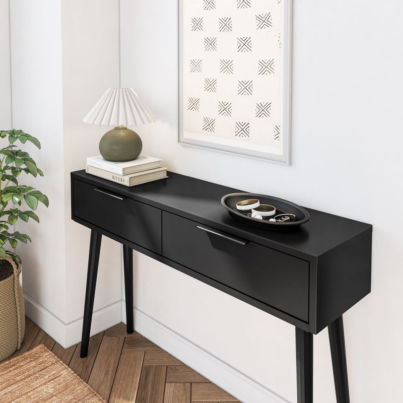 Modern black console table with decorative items and a green plant in a stylish living room setting.