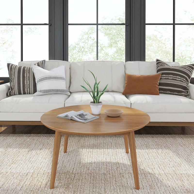 Modern living room with white sofa, wooden coffee table, decorative pillows, and potted plant.