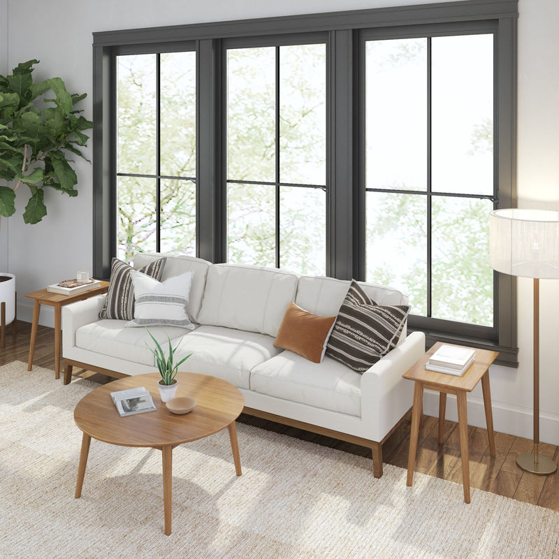 Modern living room with white sofa, wooden coffee table, and large windows.