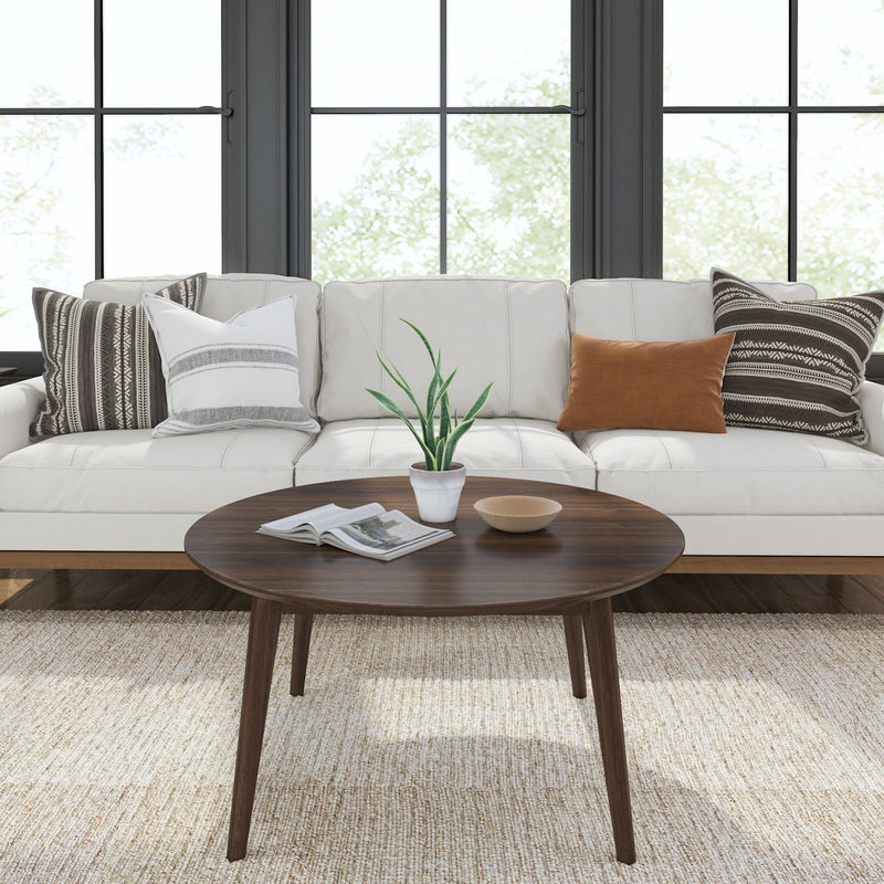 Modern living room with white sofa, decorative pillows, and wooden coffee table featuring a potted plant and magazine.