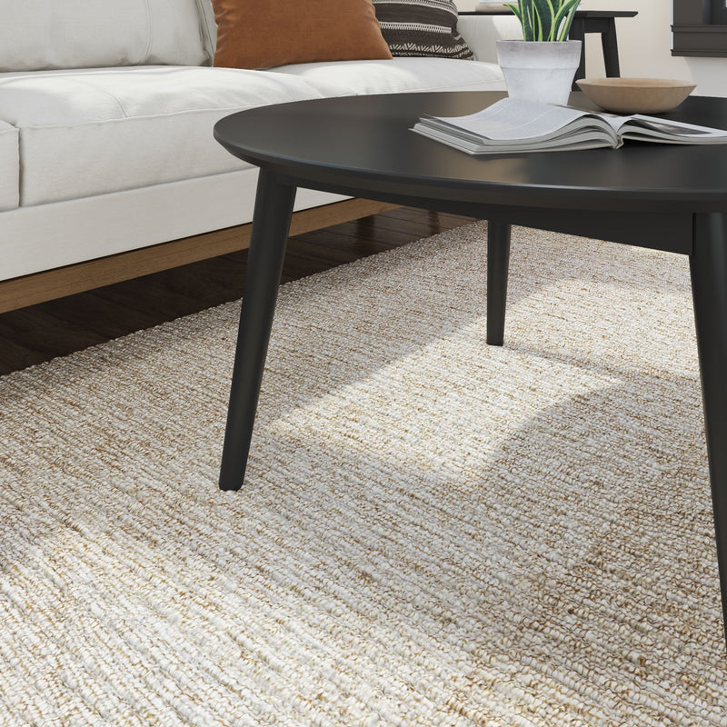 Modern black coffee table on a textured beige rug in a cozy living room setting.