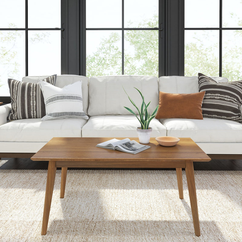 Mid-century modern living room with white sofa, wooden coffee table, decorative pillows, and a potted plant.