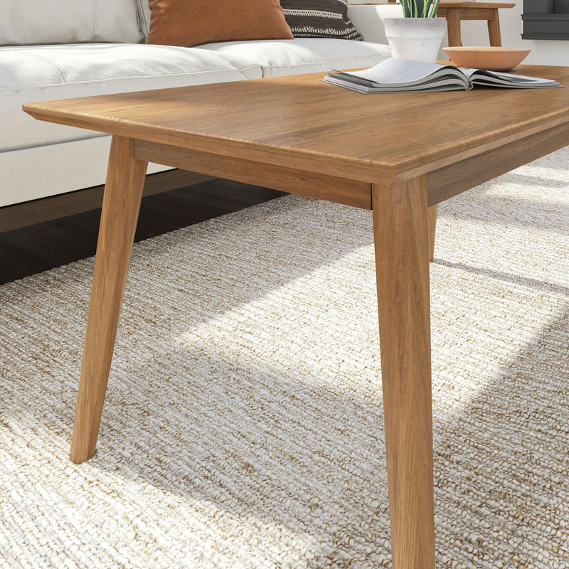 Modern wooden coffee table with open book on a light woven rug in a stylish living room.