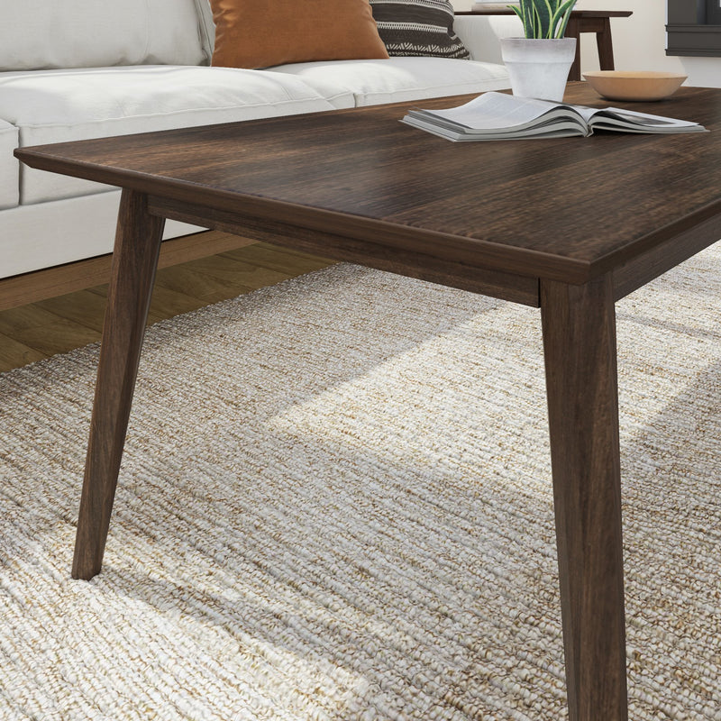 Modern wooden coffee table in a cozy living room setting with a beige rug and a white sofa.