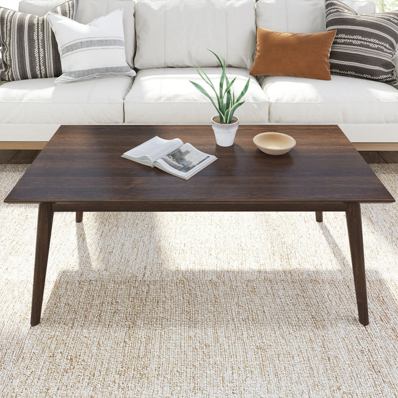 Mid-century modern living room with dark wood coffee table, white sofa, and decorative pillows.