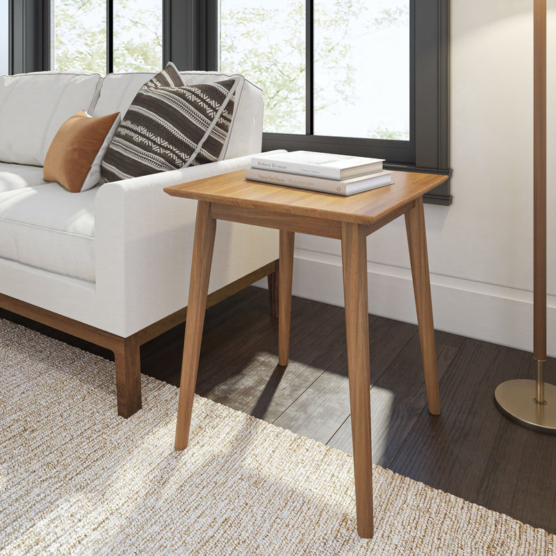 Mid-century modern wooden side table beside a white sofa in a stylish living room.