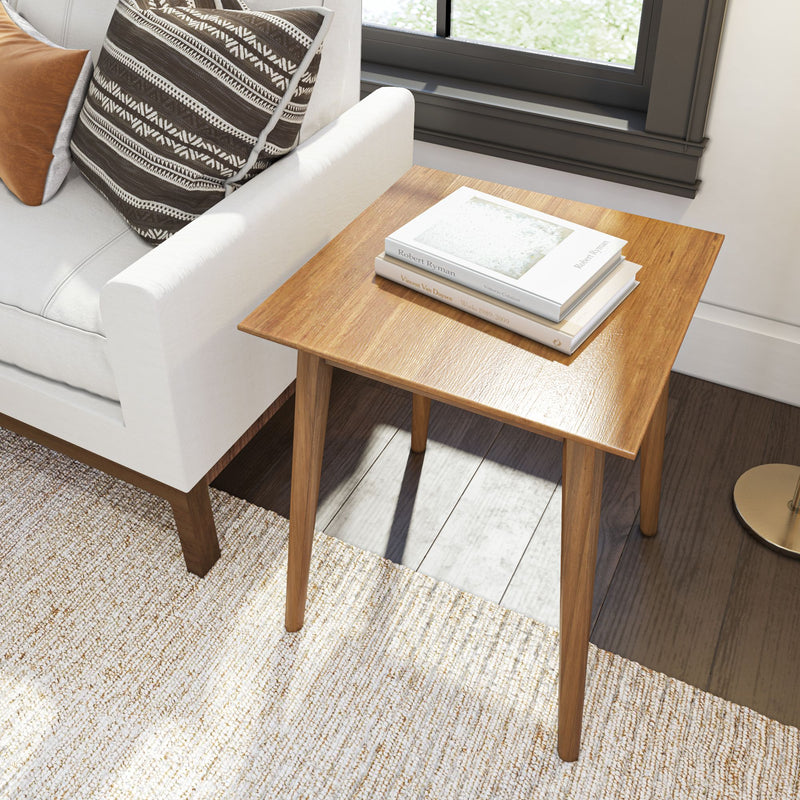 Wooden side table next to white sofa with decorative pillows, showcasing modern living room design.