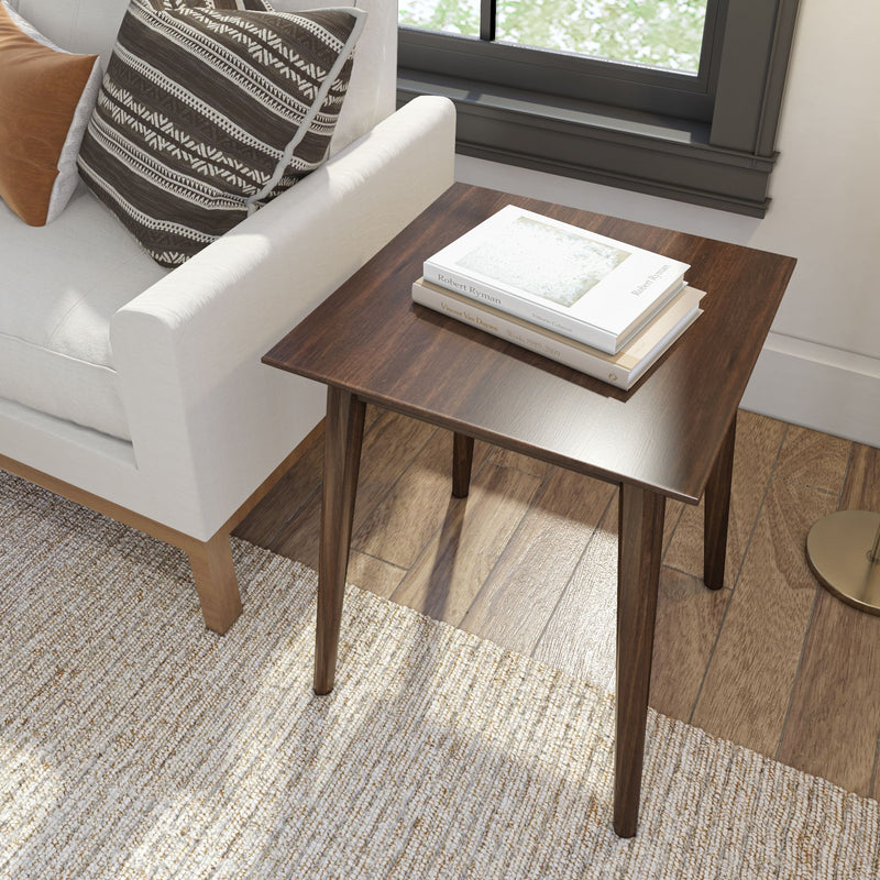 Modern wooden side table with books next to a beige sofa in a cozy living room setting.