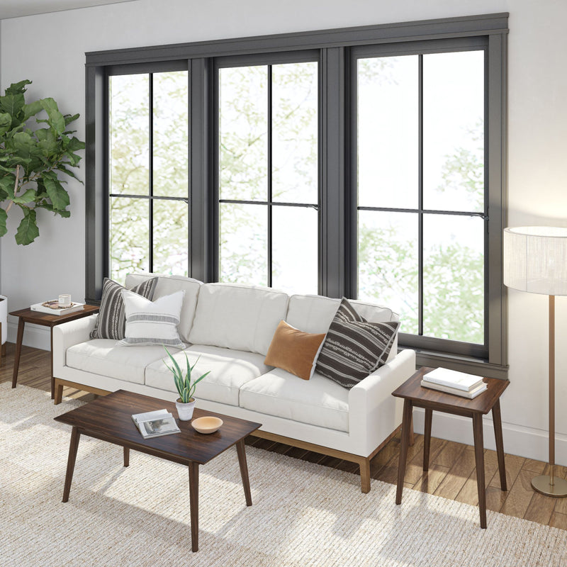 Cozy living room interior with modern white sofa, wooden coffee table, floor lamp, and large windows with natural light.