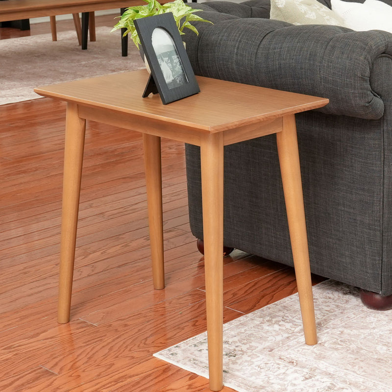 Modern wooden side table with potted plant and picture frame in living room setting.