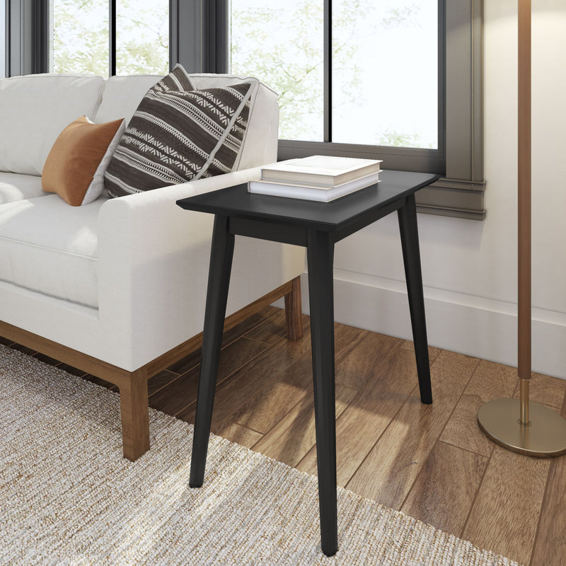 Modern black side table beside white sofa with patterned cushions in a spacious living room.
