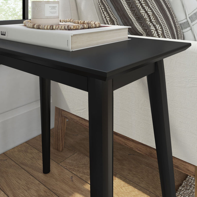 Black modern side table with books and a candle holder in a cozy living room setting.