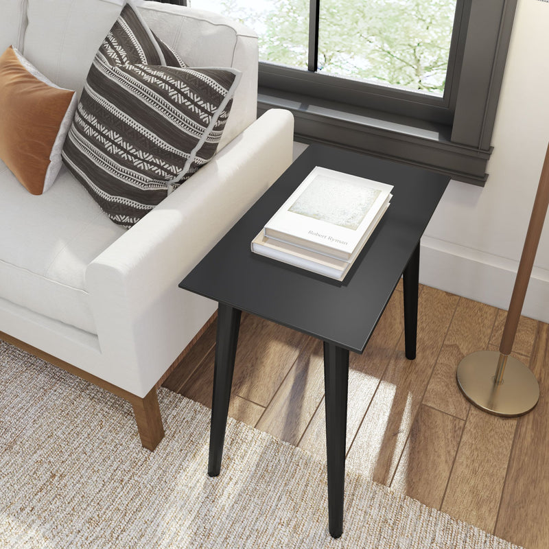 Modern living room with black side table, white sofa, and decorative pillows.