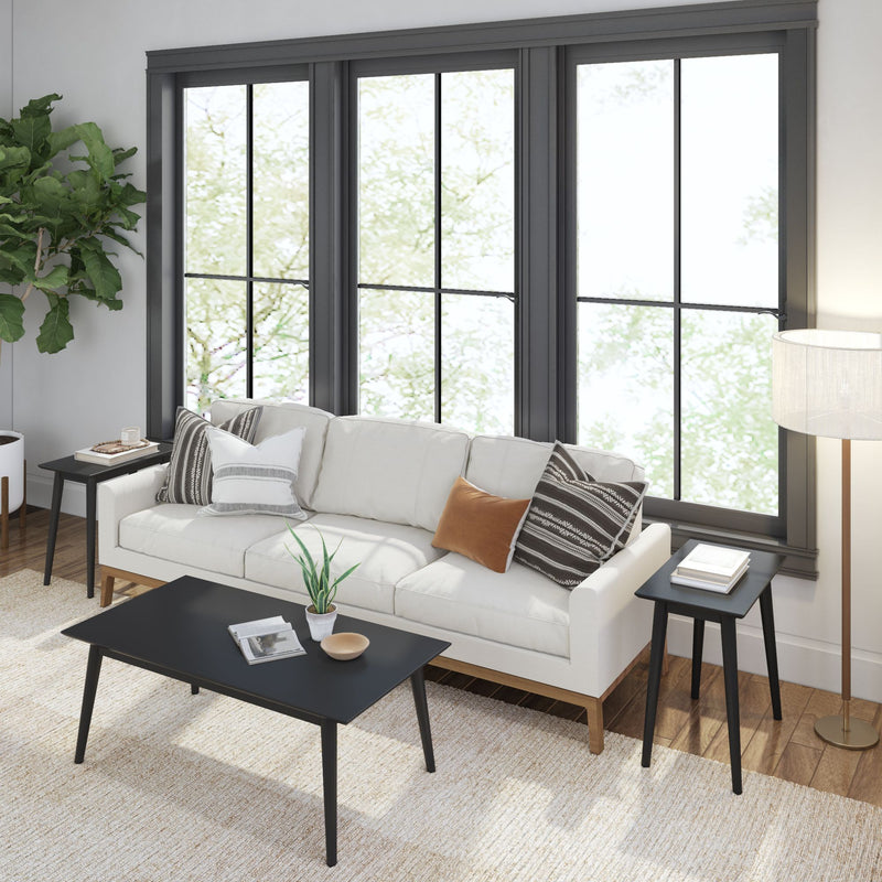 Modern living room with white sofa, black coffee table, and large windows enhancing natural light.
