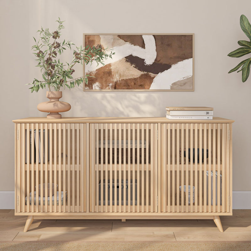 Natural oak slatted sideboard cabinet in minimalist living room with abstract wall art, ceramic vase of greenery and stacked books