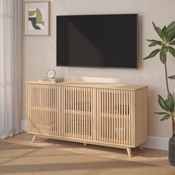 Minimalist Scandinavian light oak slatted media console TV stand with storage and mid-century tapered legs beneath a wall-mounted flat-screen TV in a neutral living room featuring framed abstract art, tabletop clock and potted plant