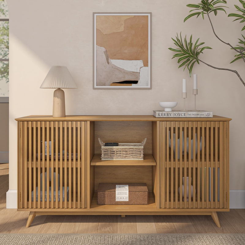 Modern wooden sideboard with slatted doors, styled with a lamp, artwork, books, and plants in a minimalist living room.