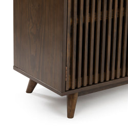 Close-up of mid-century modern walnut wood media console corner with vertical slatted doors and tapered legs