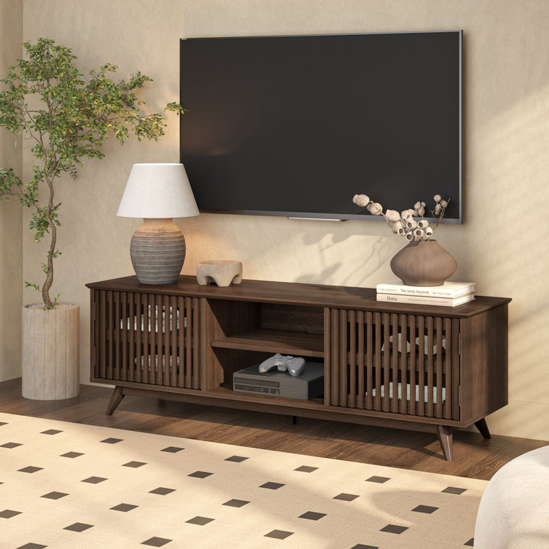 Mid-century modern living room with wooden media console, flat-screen TV, decorative plants, and table lamp.