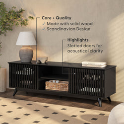 Modern Scandinavian TV stand in solid wood with slatted doors, enhancing acoustical clarity, complemented by a ceramic lamp and wicker basket arrangement.