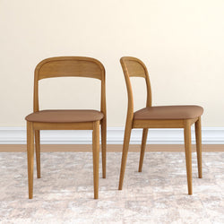 Pair of mid-century modern light wood dining chairs with brown upholstered seats on a neutral rug against a cream wall