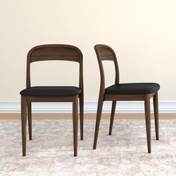 Pair of mid-century modern walnut dining chairs with black leather seats and tapered legs on a neutral rug