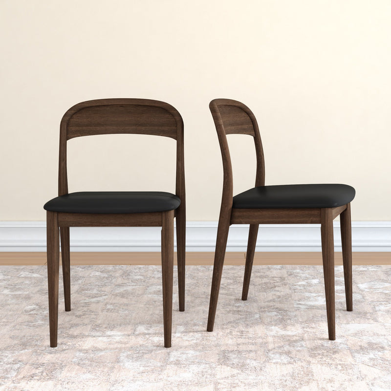 Pair of mid-century modern walnut dining chairs with black leather seats and tapered legs on a neutral rug