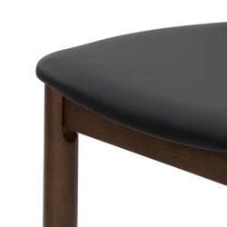 Close-up of black leather upholstered seat and walnut wood frame of a mid-century modern dining chair