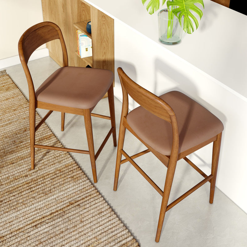 Set of two mid-century modern wooden counter stools with brown upholstered seats and walnut frames at a white kitchen island on a woven jute rug