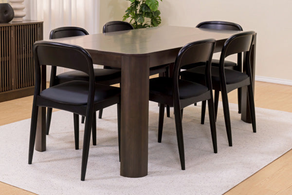 Dark wood rectangular dining table with six black mid-century modern chairs on a light beige rug in a bright contemporary dining room