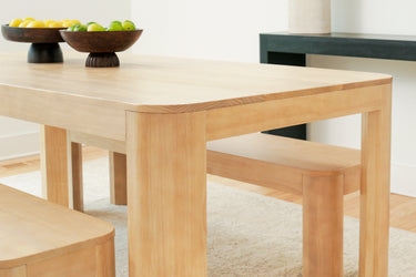 Light oak solid wood dining table with benches and fruit bowl centerpiece in minimalist dining room
