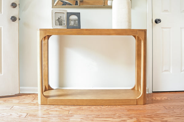 Mid-century modern light wood console table on hardwood floor in bright entryway with minimalist decor and framed photos