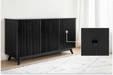 Black slatted wood sideboard storage cabinet with cable-grommet hole and tapered legs on a light rug in a modern living room