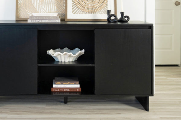 Modern black console table sideboard with open shelving displaying a white decorative ceramic bowl, stacked books and framed art on light hardwood floor