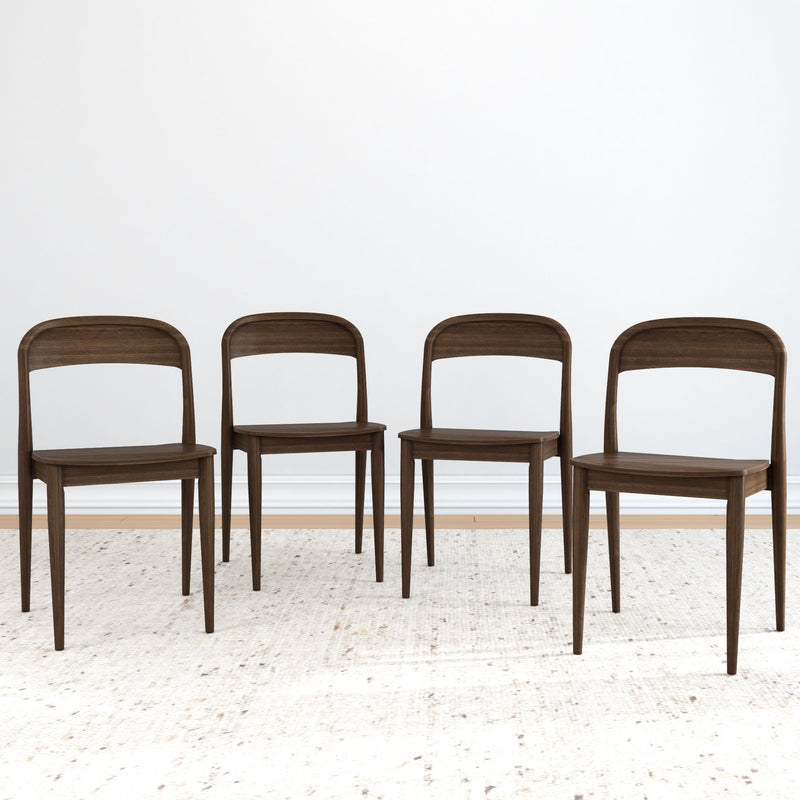 Four elegant, dark wood dining chairs on a light textured rug in a minimalist room setting.