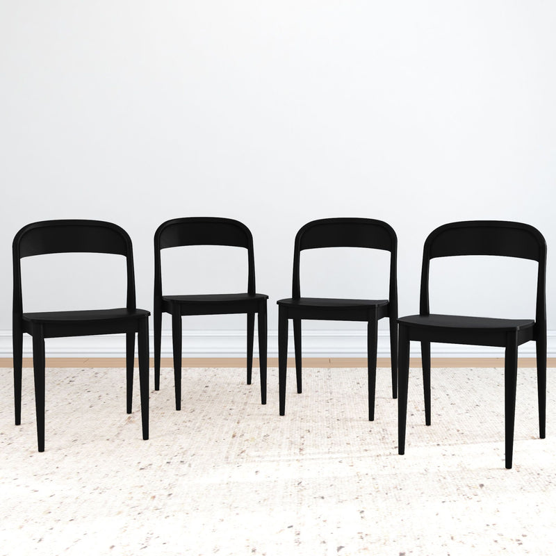 Set of 4 black modern dining chairs on a light area rug in a minimalist dining room with white wall