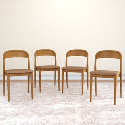 Set of 4 mid-century modern wooden dining chairs with tan upholstered seats on a neutral area rug against a beige wall — minimalist Scandinavian-style seating for dining or kitchen