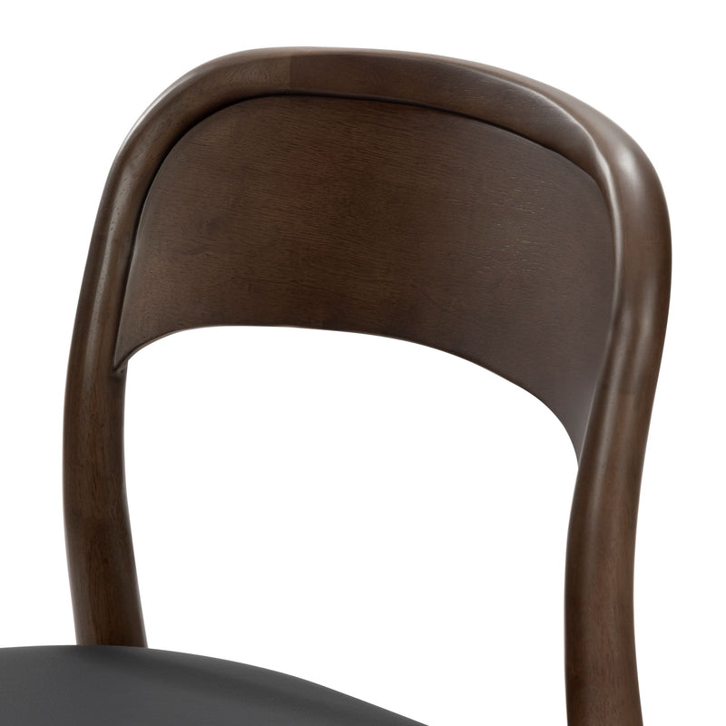 Close-up of mid-century modern walnut wood dining chair with curved backrest and black leather seat