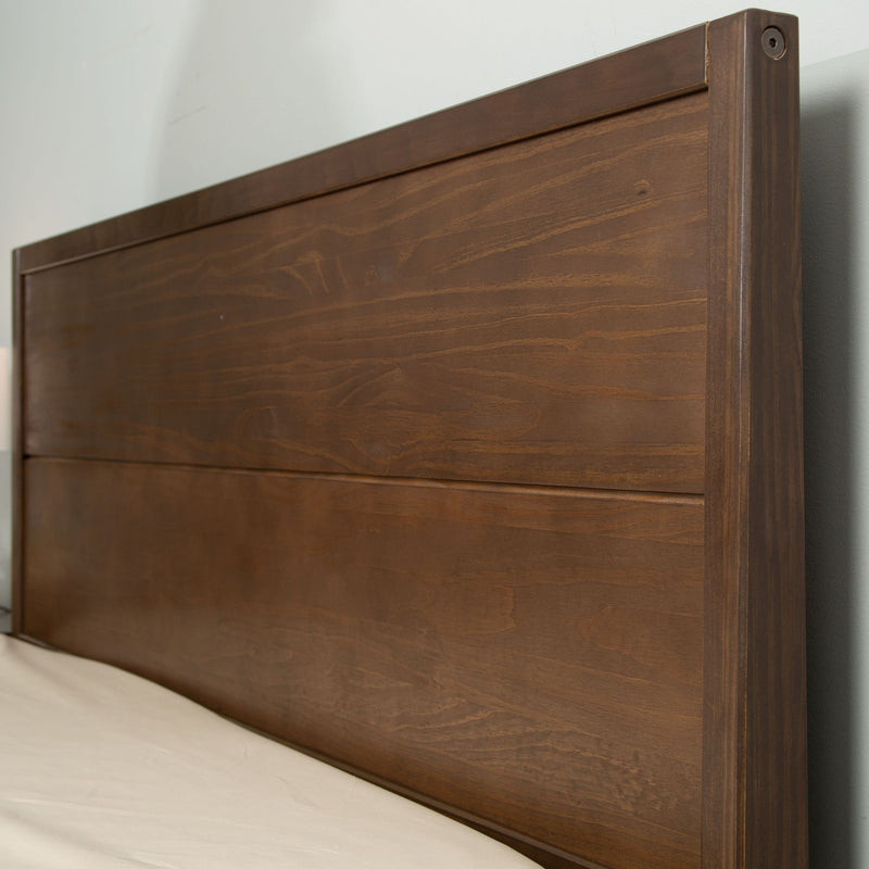 Wooden headboard with a rich brown finish against a light-colored wall.